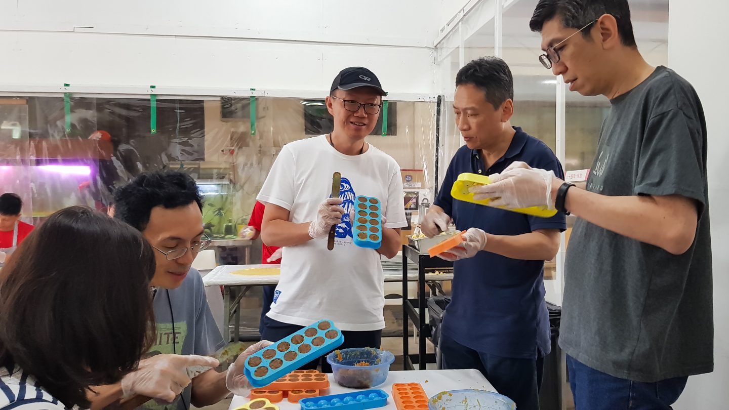 Wey Lon (second from right), together with his cell group members from Adam Road Presbyterian Church putting the pineapple jam, which has been cooked for 4 hours, into moulds. Photo by Yeo Kai Wen.