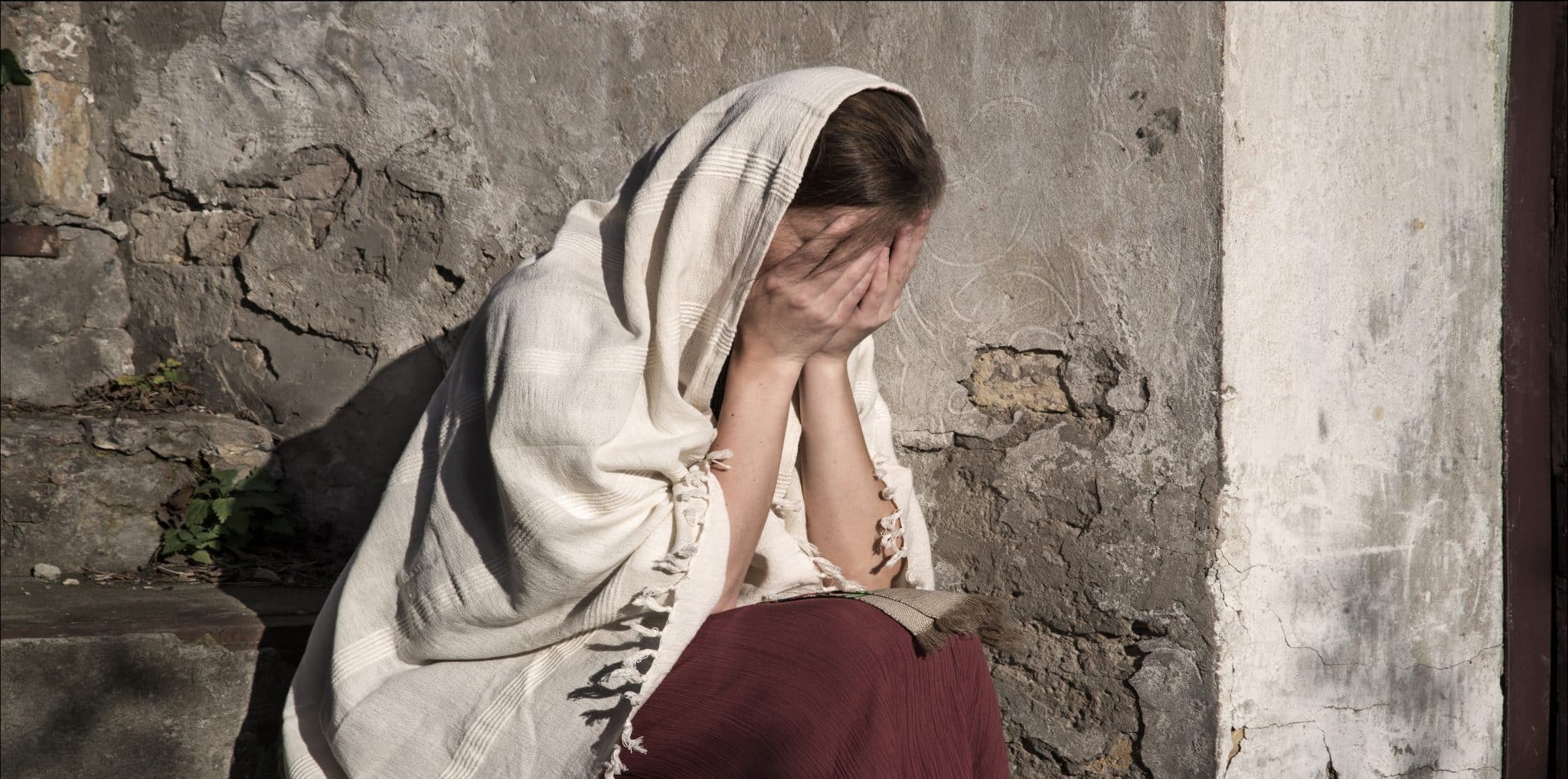 Sad woman in ancient clothes sitting on the steps